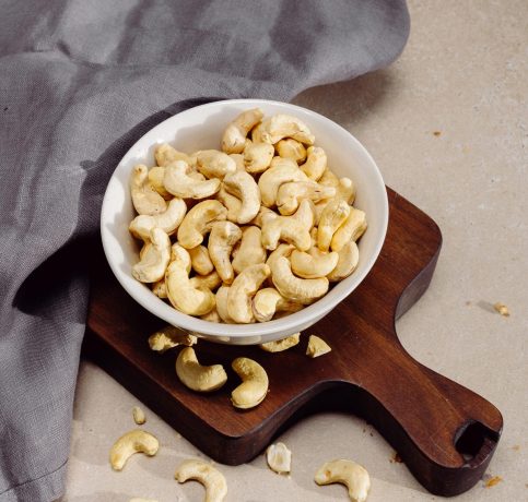 Top view of cashew nuts in a bowl on a wooden cutting board, perfect for healthy snack concepts.